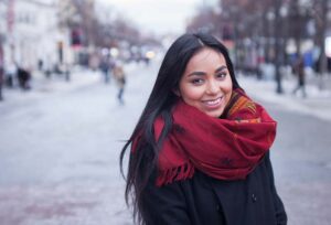 Brunette Asian girl in a red scarf on a snowy street that has recently immigrated to Canada