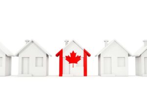 Row of toy houses with one house painted like a Canadian flag