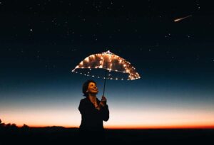 A person standing under a lit up umbrella