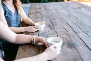 Two women sitting at a table drinking coffee communicating