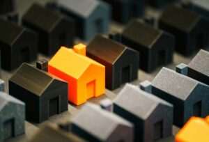 Orange Monopoly toy house in a group of black houses