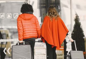 Two travelers arriving at the airport with their luggage
