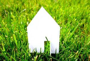 Cutout of a paper house sitting on the grass: Why Relocation Policies Do Not Behave Like Other HR Policies